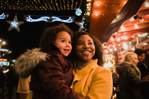 Uma mulher e uma criança com luzes de natal atrás