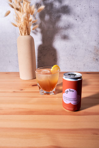 Can of De Soi Champignon Dreams next to non-alcoholic mocktail with a lemon wedge