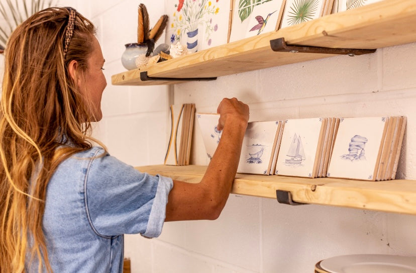 Artist looking at a shelf of modern Delft style blue and white painted tiles