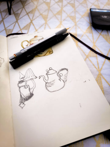 an open sketchbook page with a sketch of a teakettle and teabag that have mushrooms growing out of them. 