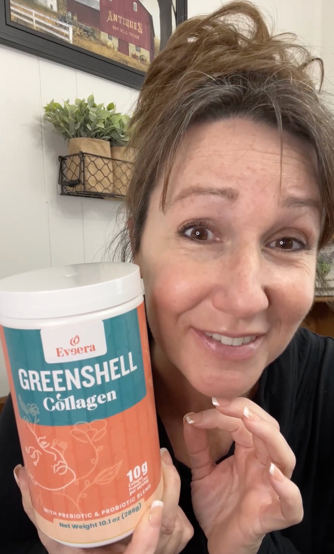 Woman holding a container of Greenshell Collagen with a friendly smile.