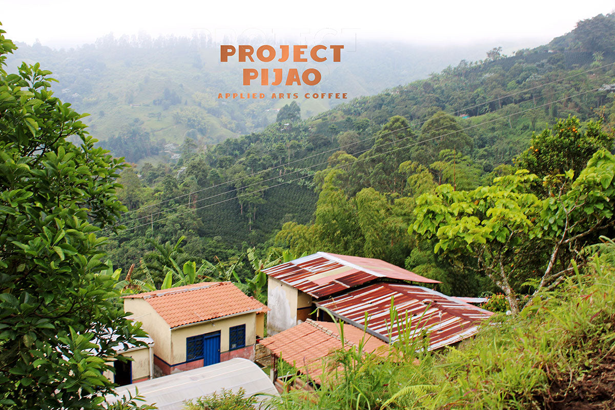 El Tesorito Farm in Pijao Colombia seen from above.  El Tesorito farm is the family coffee farm for Applied Arts Coffee/ Project Pijao.  Mountains, buildings nestled in beautiful Colombian mountain setting.  Project Pijao by Applied Arts Coffee written in copper.