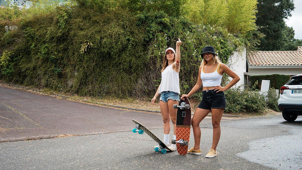 two girls holding surfskates flipping off the photographer in australia