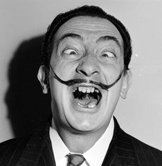 Salvador Dali smiling in a funny face with his mustache