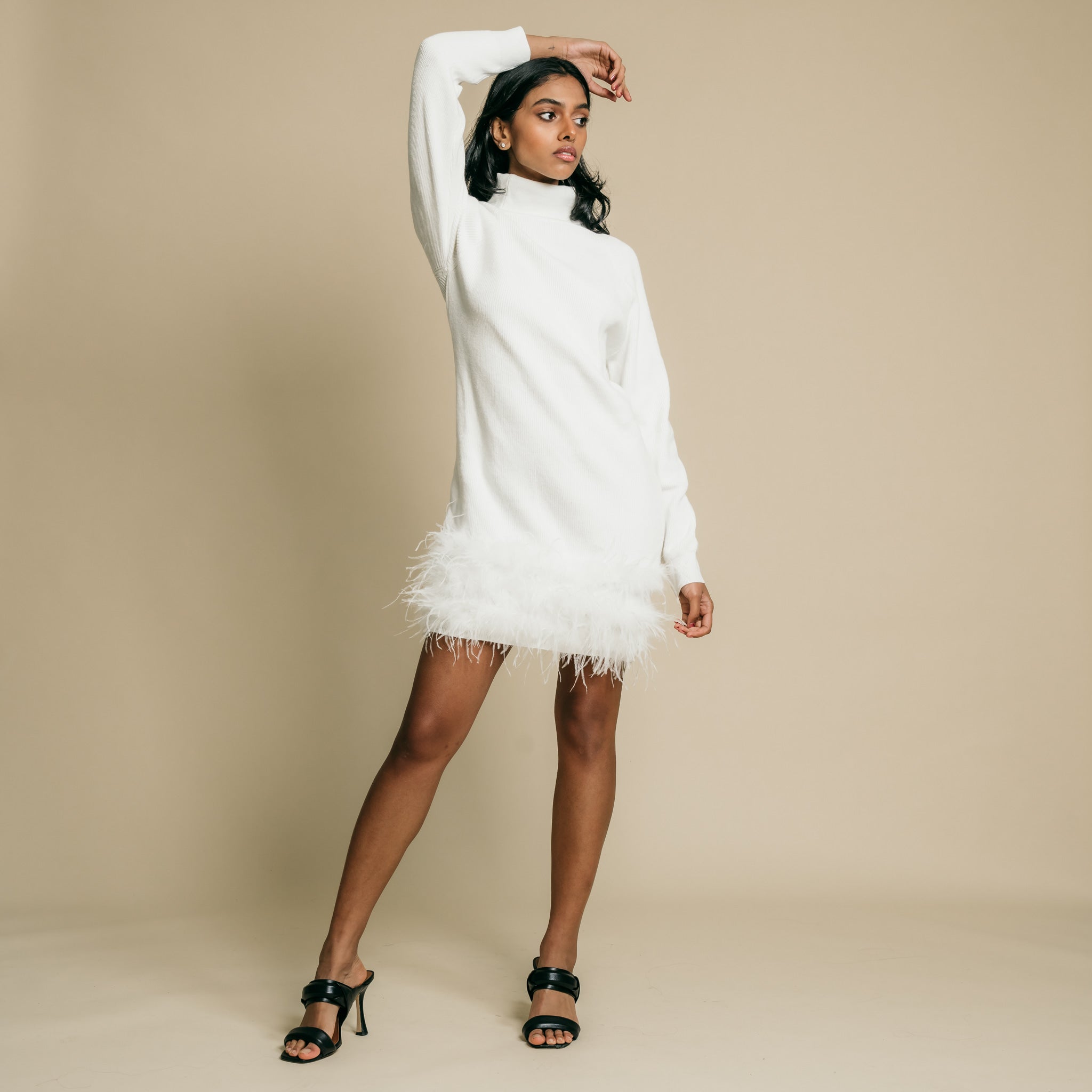 White, turtleneck, long sleeve, knit mini dress featuring feather on front side of hem.