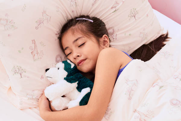 Child sleeping with a plushie and tucked into bed with Evercool Kids Cooling Comforter and pillowcase in animal friends design