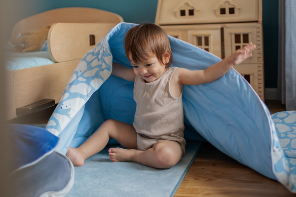 Toddler playing, with the Evercool Kids Cooling Comforter in polar bear design draped over their shoulder