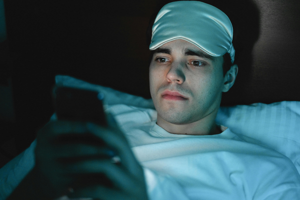 Person preparing to sleep but using their phone in bed