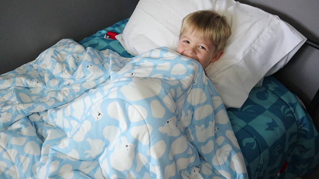 Child in bed under the covers of Evercool Kids Cooling Comforter in polar bear design
