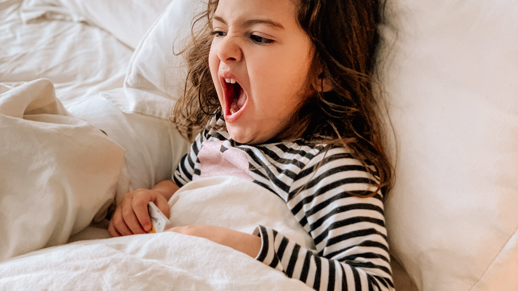 child yawning in bed