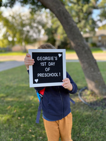 Child holding sign that says First Day of Preschool.