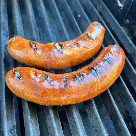 Two chorizo sausages grilling on a bbq.