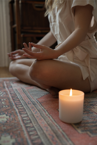 woman meditating with a candle beside her