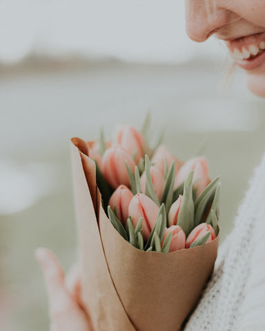 Ostergeschenke für Erwachsene: Eine Frau, die einen Strauß Blumen in der Hand hält.