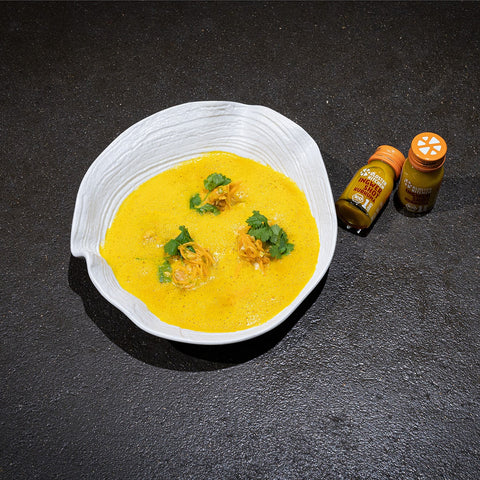 Angerichtete Süßkartoffel Suppe. Daneben stehen 2 Ingwer Shot Kurkuma.