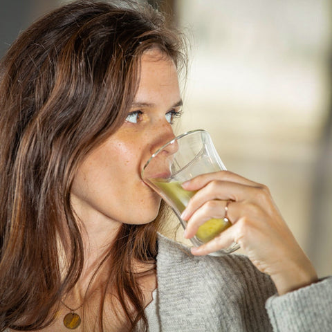 Donna che beve un bicchiere di latte dorato