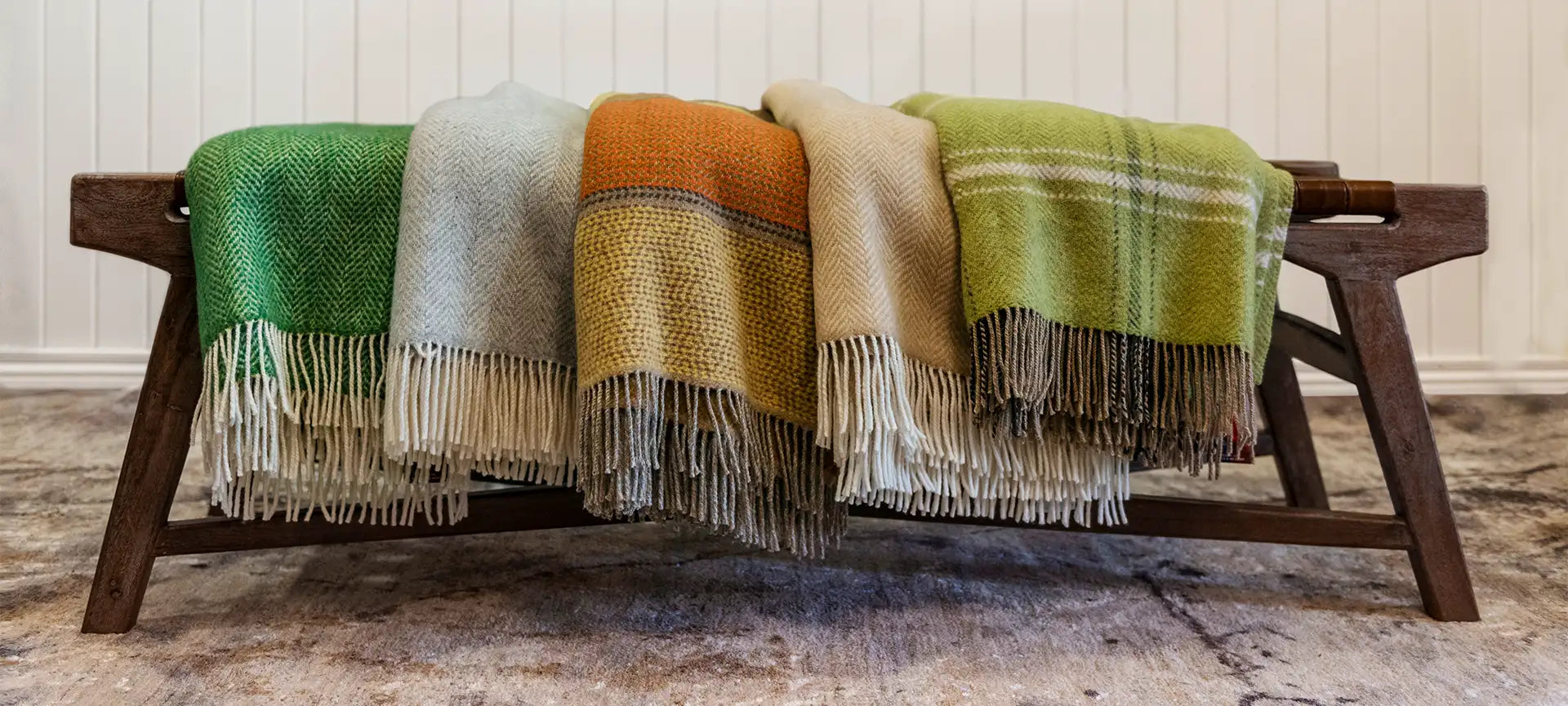The Drapery Haus Cork - 5 different coloured Couch Throws draped over a bench