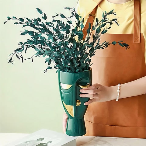 Vase en forme de visage style nordique modèle Vert doré avec fleurs tenu en main