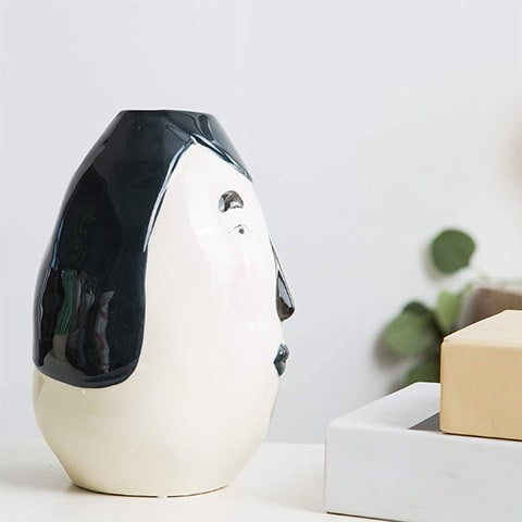 Vase ovale blanc visage original en céramique présentation de profil sur une table