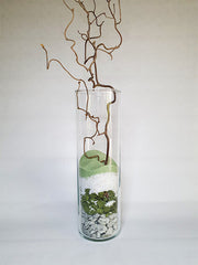 Vase transparent décorer avec du sable vert et blanc et des galets et branches