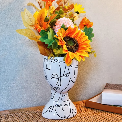 Vase visages abstraits original en céramique présentation sur table avec bouquet de fleurs fraîches