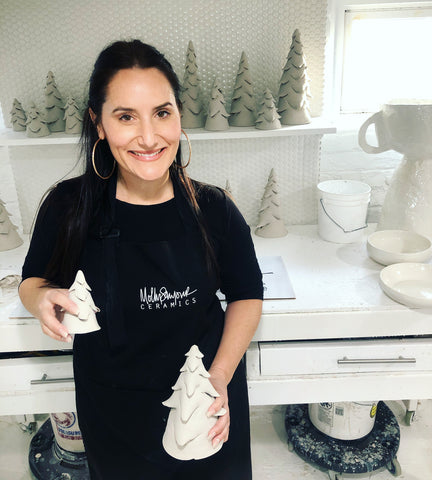 molly sanyour in her pottery studio holding up work she made