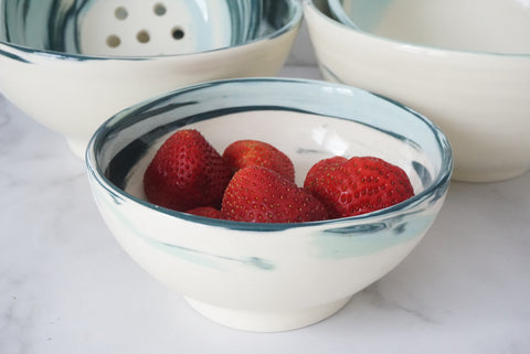 Blue colored clay swirled wheel thrown bowl with strawberries in it