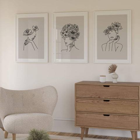 Set of three neutral prints with line drawn lady's face outlines, framed on wall