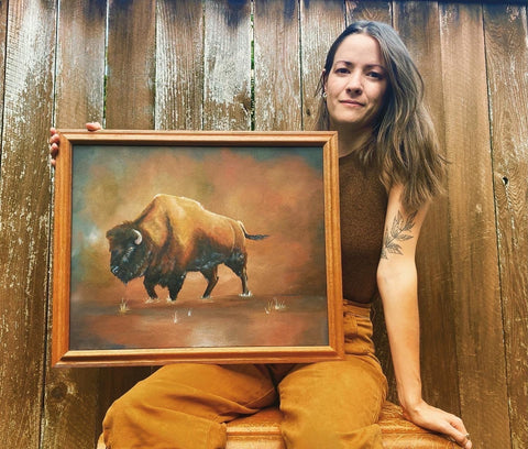 Photo of Ashley Miller holding a painting she painted of a buffalo