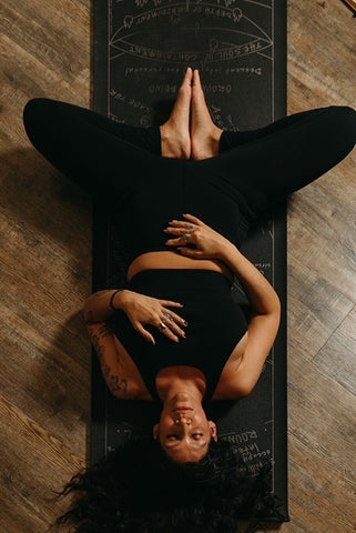 Marla laying on her back, on a mat. Feet together, arms on her stomach and chest, focusing on her calm breath. 