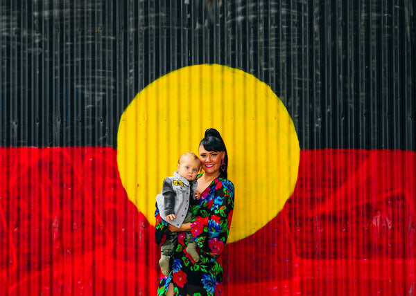 Kristy Dickinson and son, Ziggy in front of an Aboriginal Flag painting