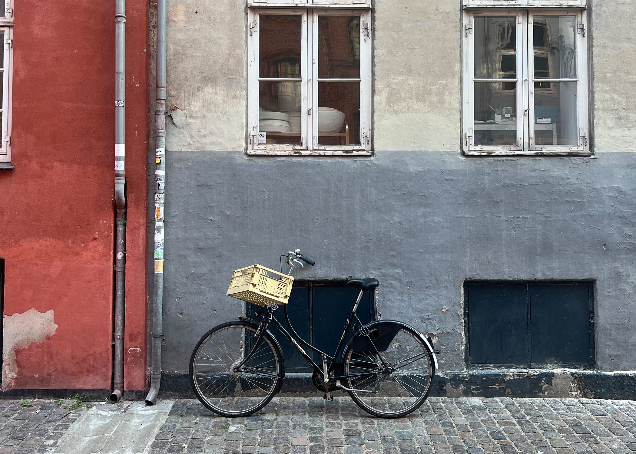 A bicycle rests against a red and grey building in Copenhagen, Denmark