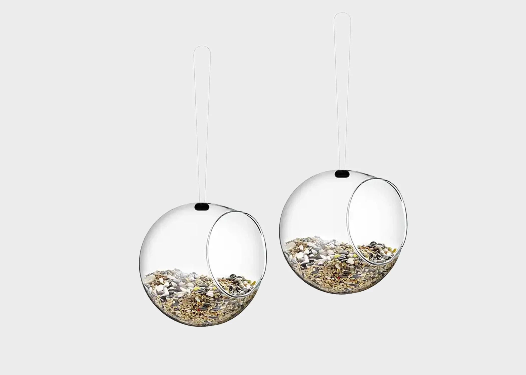 Two orb bird feeding glass balls by Eva Solo filled with bird seed