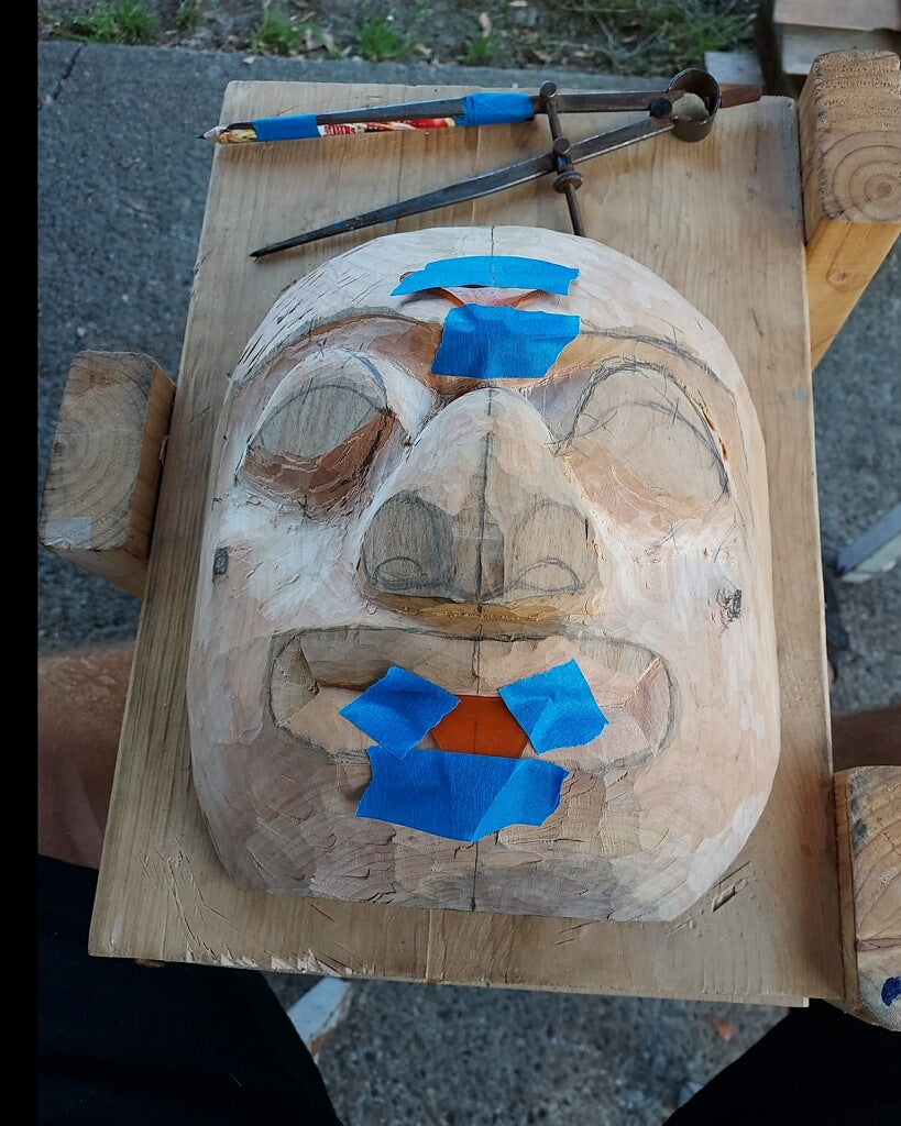 Fred Fulmer Tlingit Artist balancing the Changing of the Tides mask with blue tape for measuring