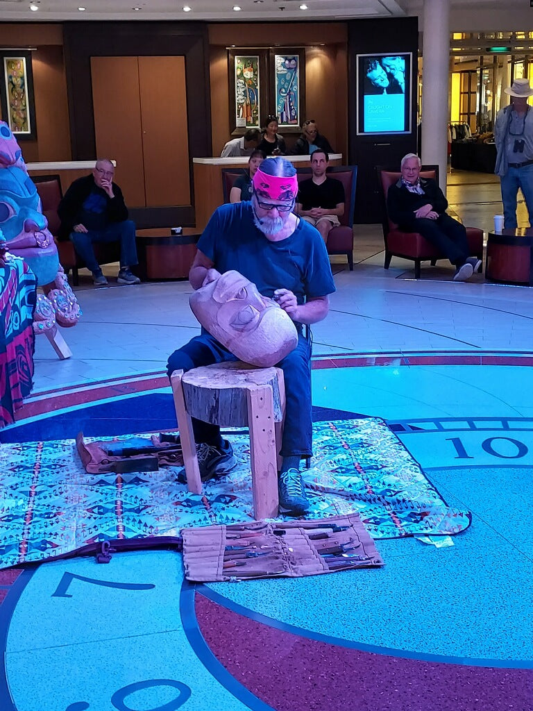 Fred Fulmer Tlingit Artist & Carver carving the Spirit of Glacier Bay Mask in front of a crowd on a cruise ship