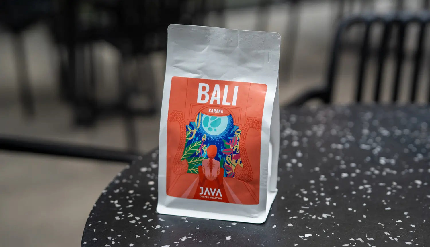 Opakowanie kawy specialty JAVA Coffee Roasters – Bali Karana 250g, jasno palona kawa z Indonezji, sfotografowana na stoliku w kawiarni.