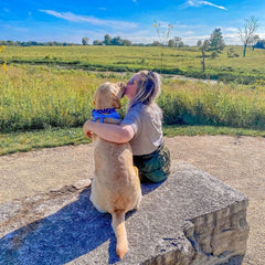 Young woman and dog sitting on a rock