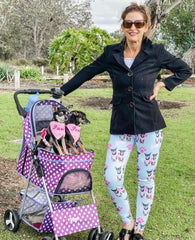 Woman standing next to a stroller with two small Chihuahua dogs in the stroller