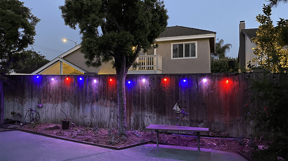 Backyard with Feit Electric Smart String LED Lights glowing in red, white, and blue light.