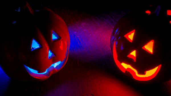 Two carved jack-o-lanterns emitting colorful glow