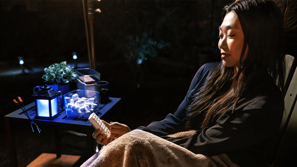 Young woman sitting outdoors in chair holding a OneSync Handheld Remote Control.