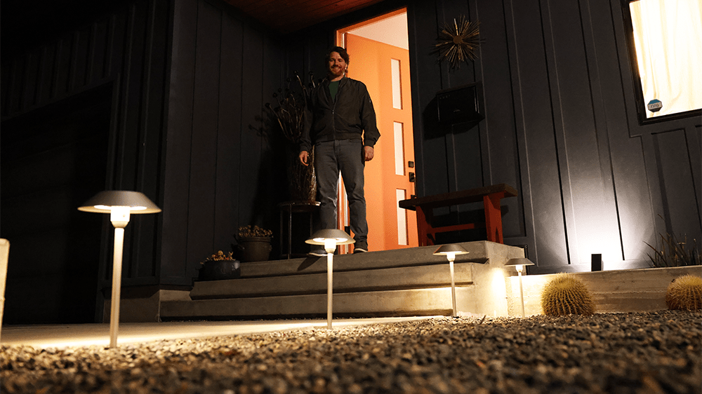 Man standing at front door looking at OneSync Solar Powered Pathway lights.