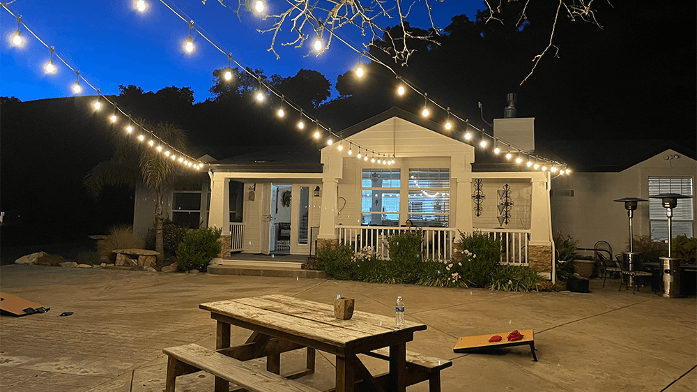 Spacious backyard at night with LED string lights hanging overhead.