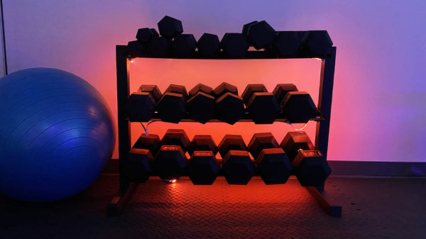 Weight rack against the wall with blue ball next to it and orange light glowing behind.