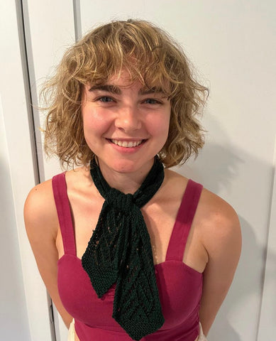 Rachel wearing a dark green Versailles Scarf and pink tank top, smiling at the camera