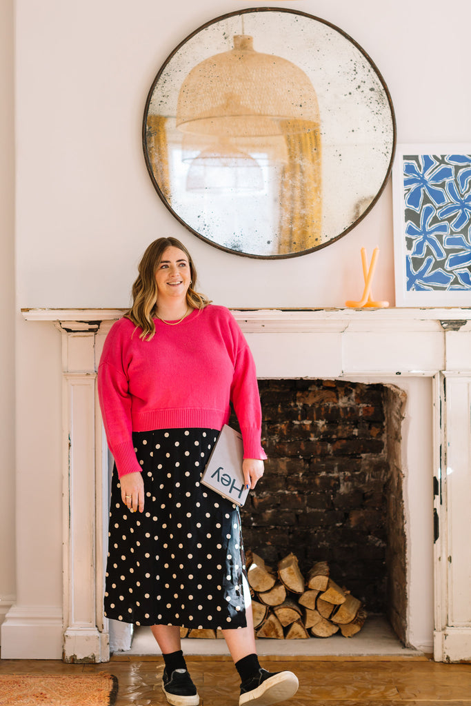 Weekend IN founder Olivia standing in front of a fireplace in pink jumper