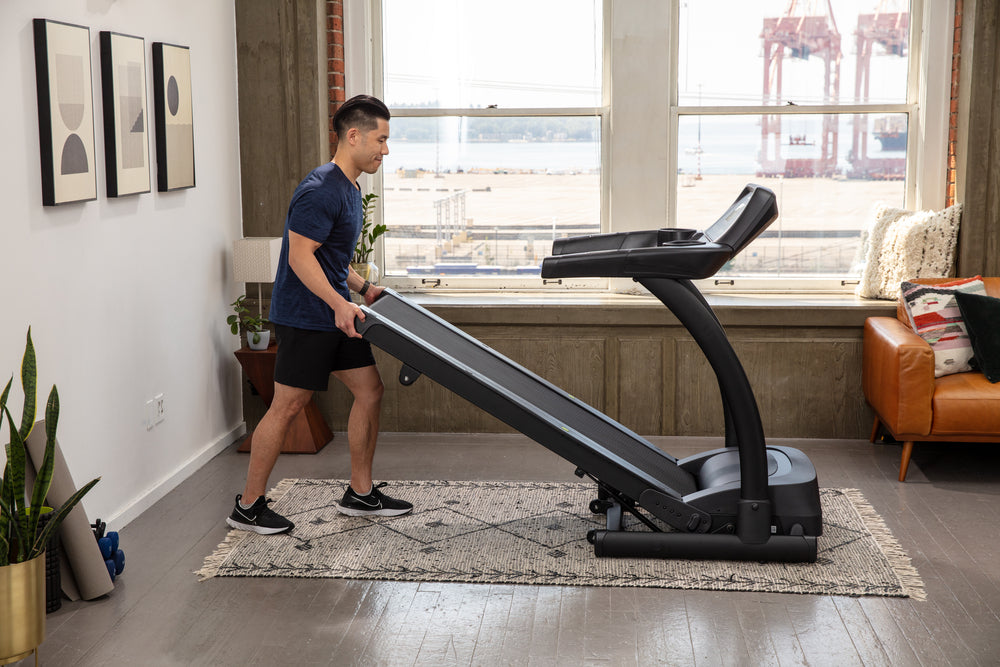 Sportsart TR22f Folding Treadmill with male folding the treadmill up