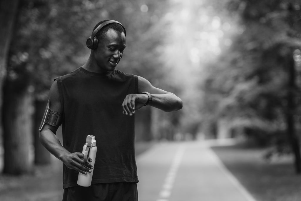 Man checking his fitness device and hydrating.