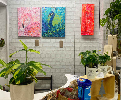 Bright bird paintings hanging on a wall in a plant shop