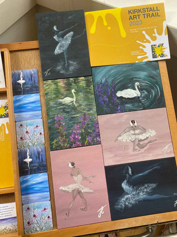 A collection of small paintings of swans and ballerina swans with the yellow KAT flier
